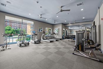 A spacious gym with a variety of equipment and a view of a cityscape outside the window. at 46 Penn Apartment Homes, Kansas City, Missouri